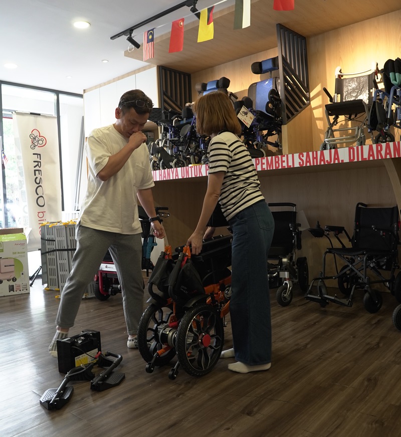 Couple testing an electric wheelchair in a Malaysian store. Electric wheelchair test drive.