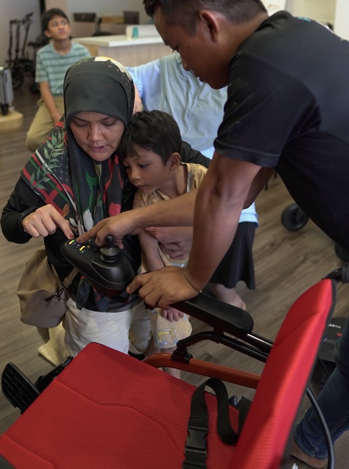 Family testing electric wheelchair controls; electric wheelchair Malaysia.
