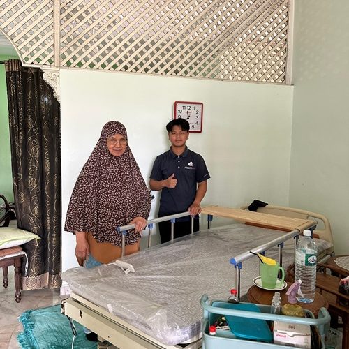 Home healthcare worker assisting elderly woman with hospital bed setup.