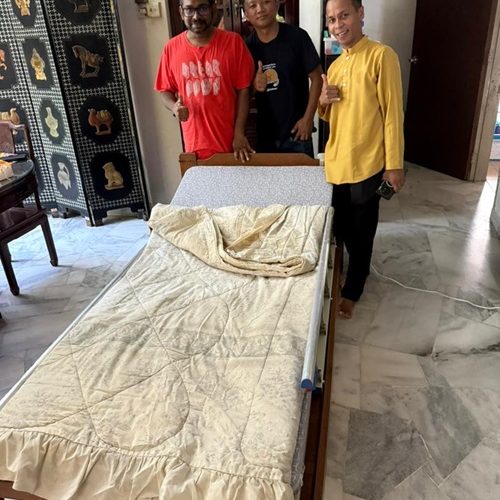 Three men smiling with a hospital bed. Home healthcare delivery.