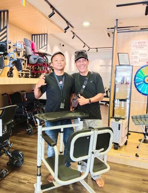 Two men smiling next to a mobility aid chair in a store, showcasing assistive devices.