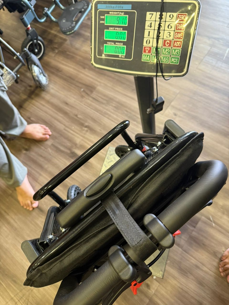 Fresco Bike travel wheelchair weighing 9.1 kg on a scale. Lightweight and portable design.