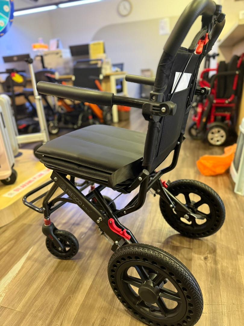 Black Fresco Bike travel wheelchair, lightweight and portable, shown from the side.
