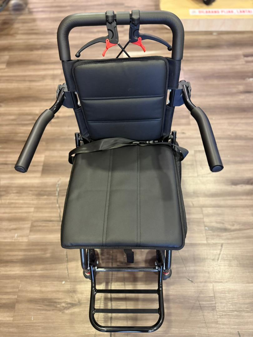 Black Fresco Bike travel wheelchair, lightweight and compact, with folding armrests and footrests. Ideal for elderly or travelers.