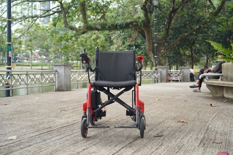 Lightweight carbon fiber electric wheelchair outdoors in a park.
