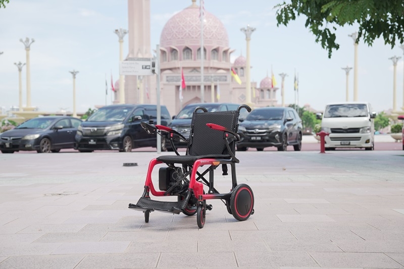 Lightweight carbon fiber electric wheelchair parked outdoors.