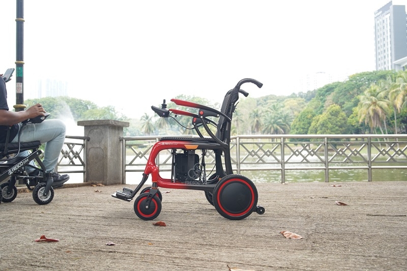 Sleek red and black carbon fiber electric wheelchair outdoors. Lightweight and ideal for elderly care.