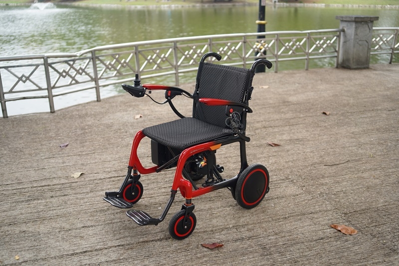Lightweight carbon fiber electric wheelchair outdoors near a pond.