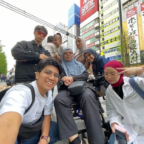 Multigenerational family smiles for a selfie in Akihabara, Tokyo, in front of a game store.