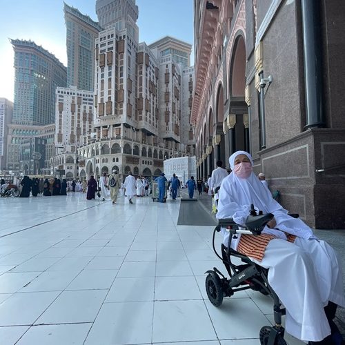 Person in a wheelchair in front of Abraj Al Bait Towers, Mecca