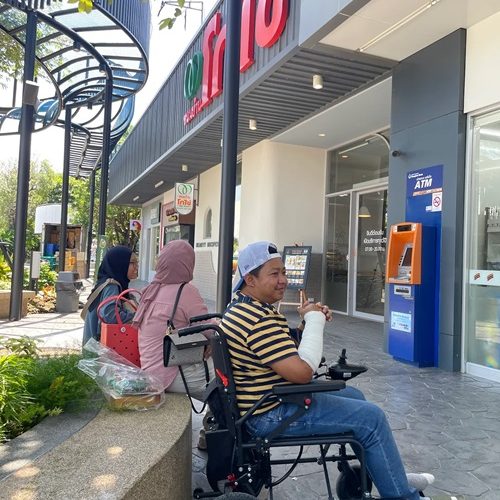 Man in wheelchair outside convenience store with friends